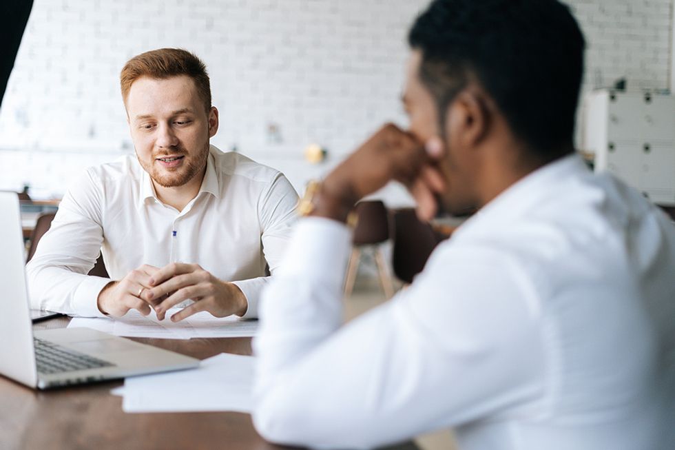 A boss listens while his employee shares an idea with him during a work meeting