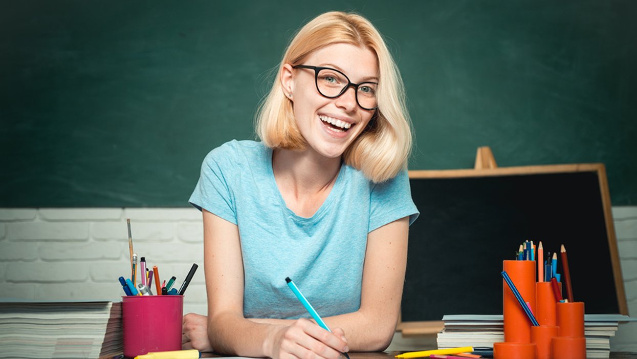 A happy young teacher grades an assignment from one of her students