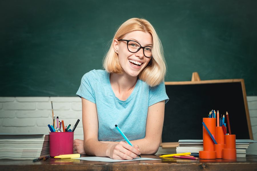 A happy young teacher grades an assignment from one of her students