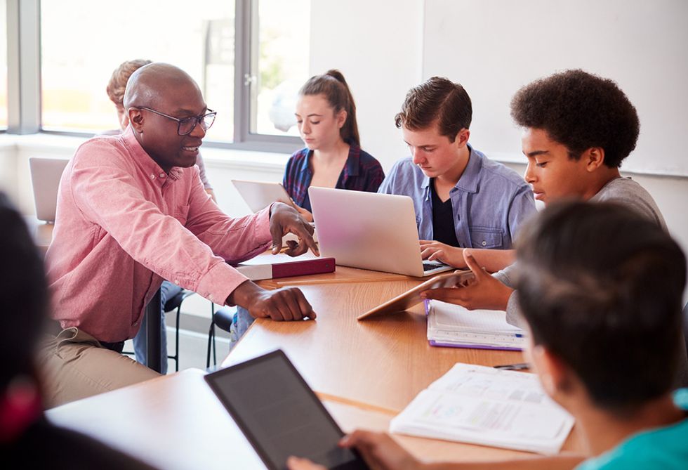 A high school teachers shows his students how to use new technology in the classroom