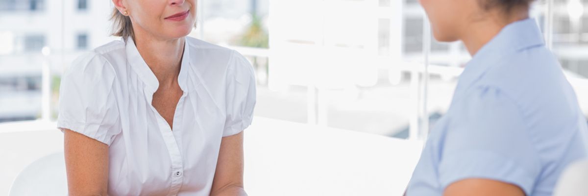 A hiring manager listens and takes notes during a job interview.