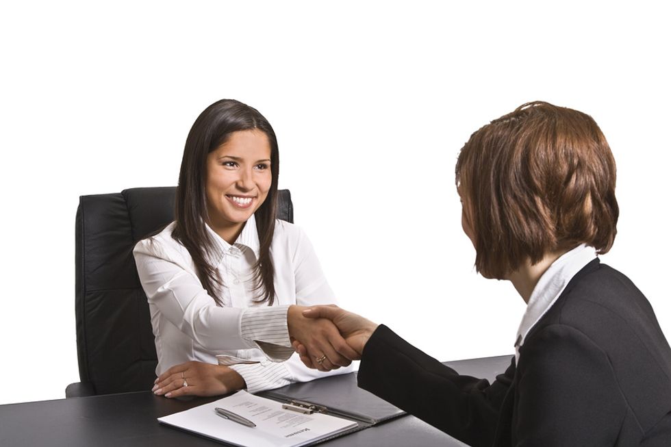 A human resources manager shakes hands with a job seeker during an interview.