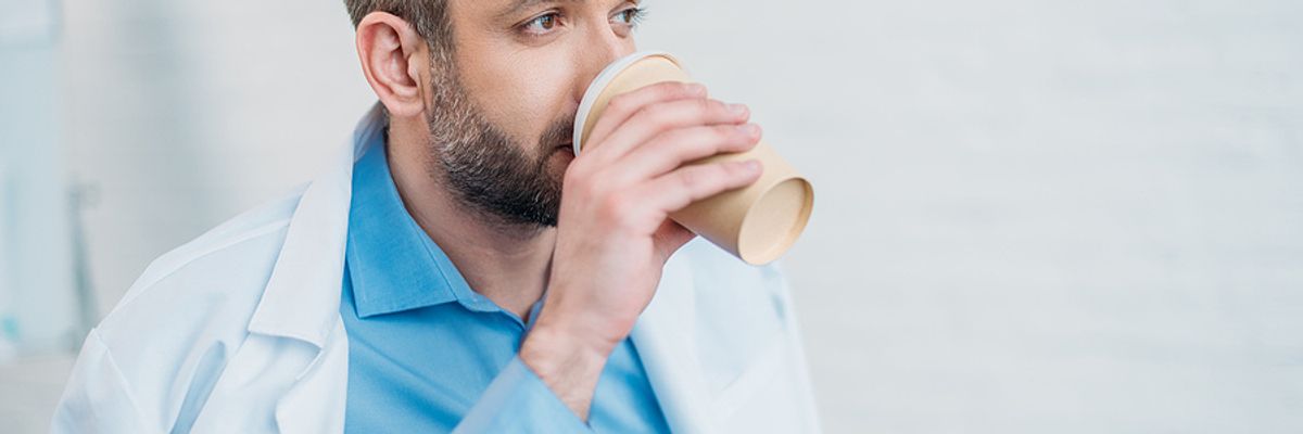 A tired doctor enjoys a cup of coffee.