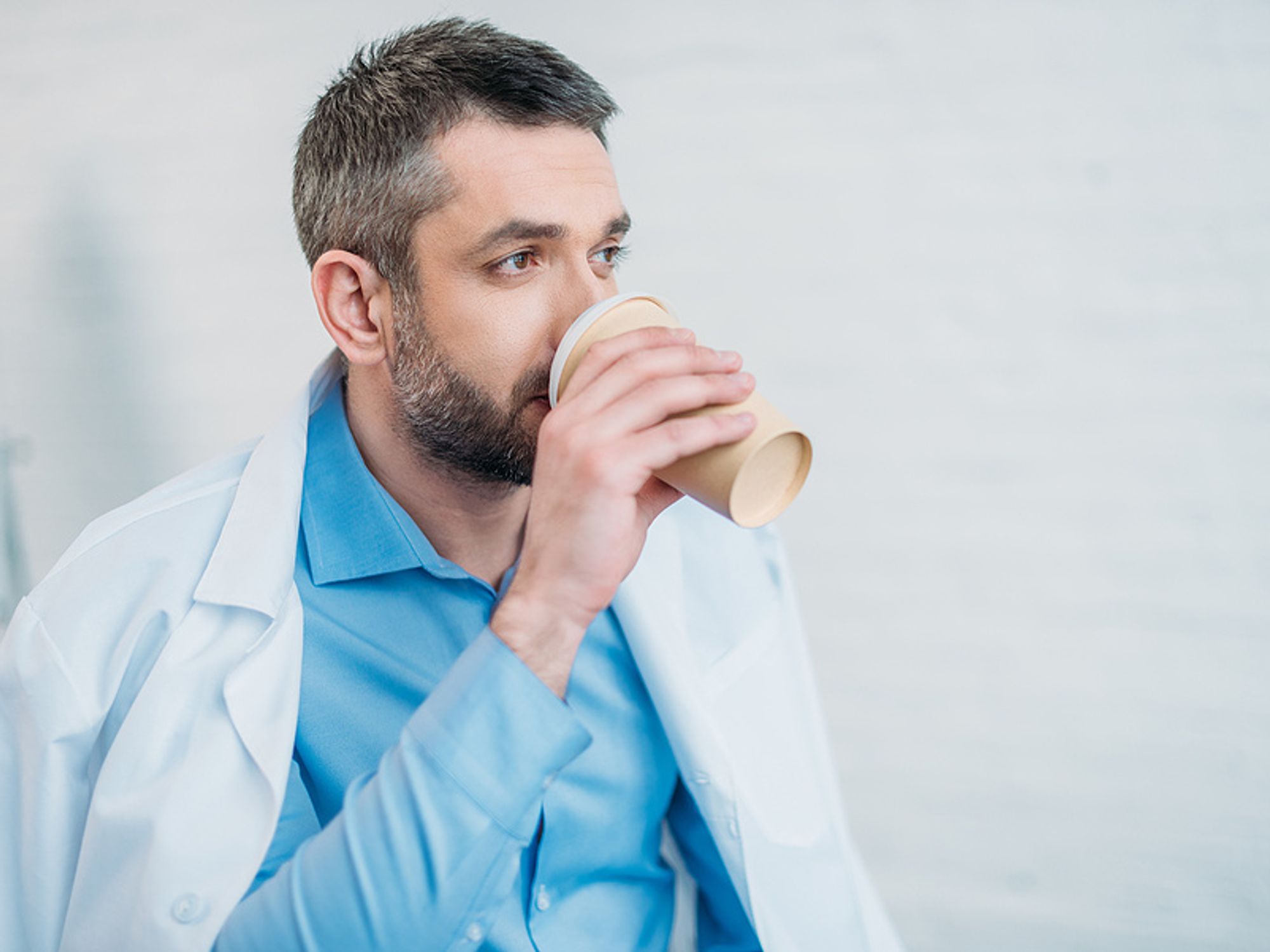 A tired doctor enjoys a cup of coffee.