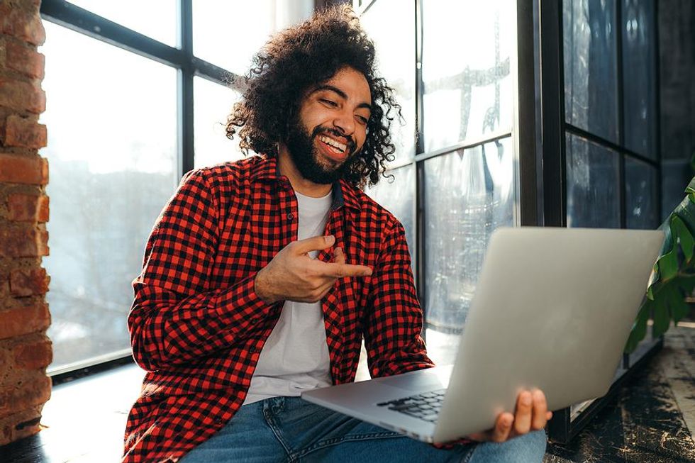 A young professional on a laptop interacts with others on social media