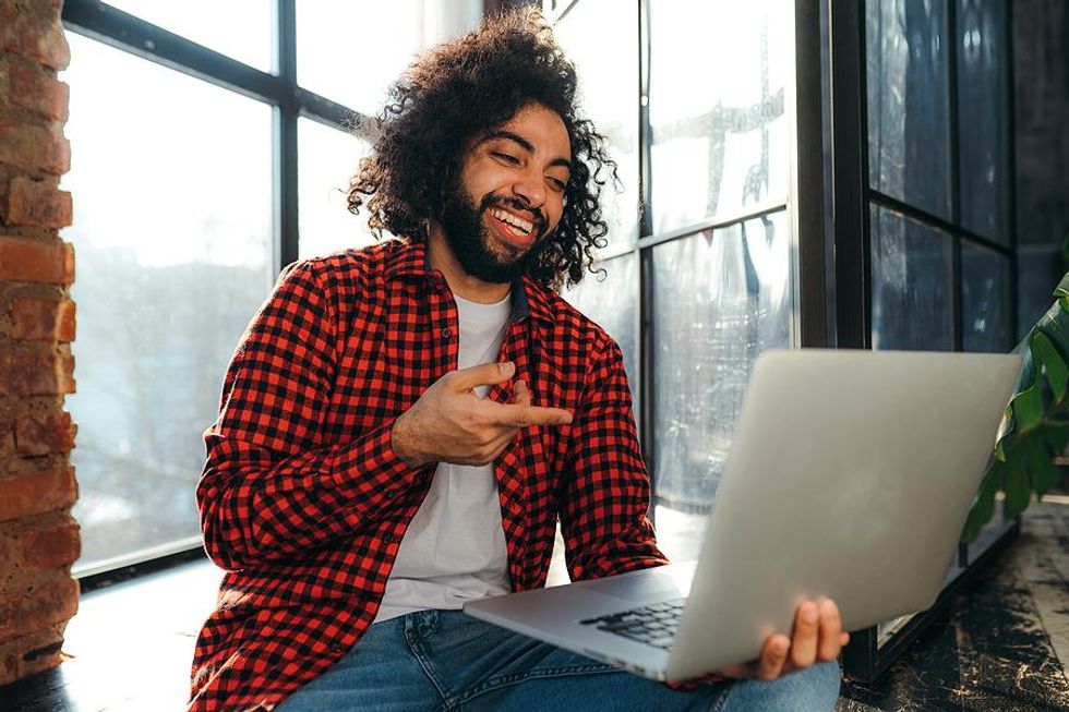 Un jeune professionnel sur un ordinateur portable interagit avec d'autres sur les réseaux sociaux