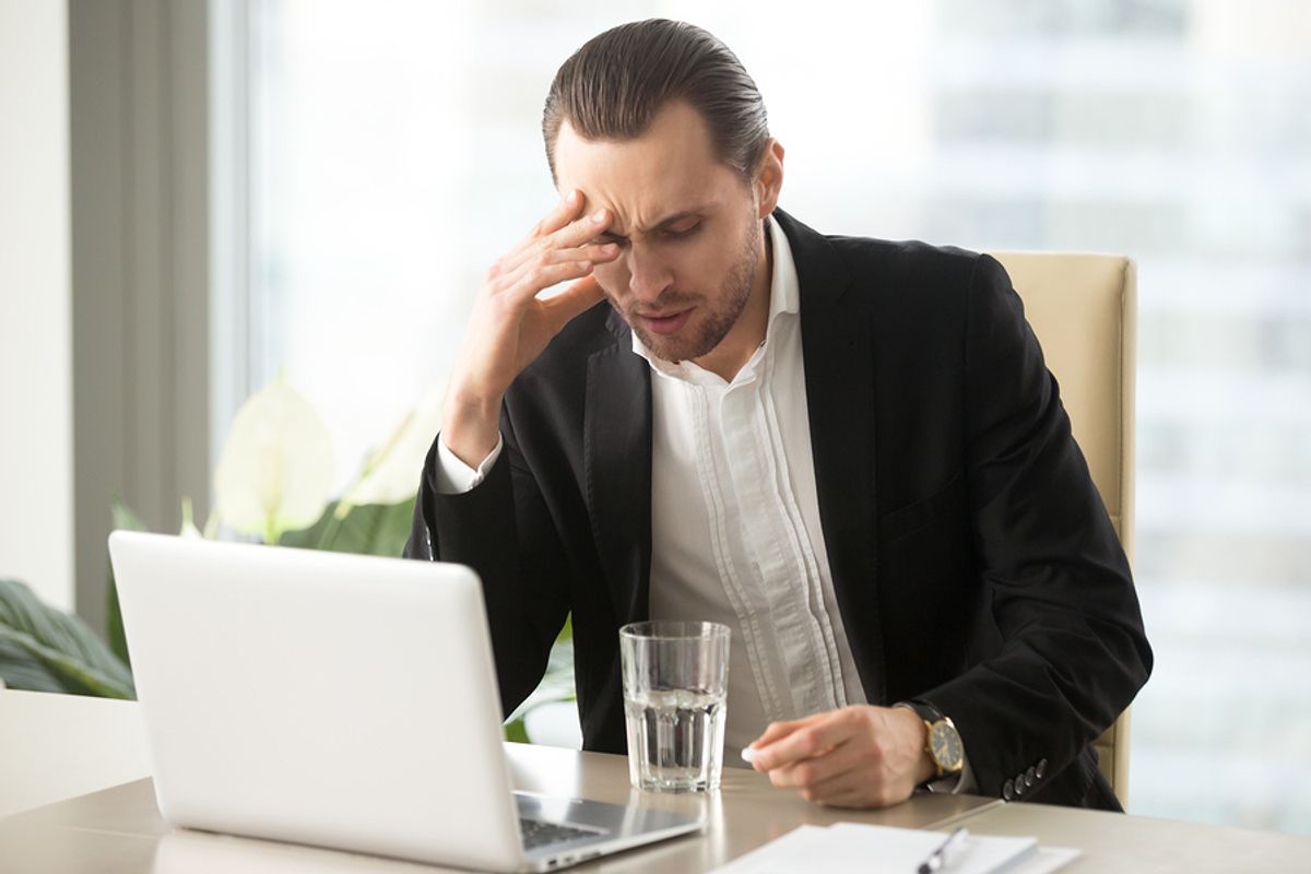 An executive working long hours shows signs of stress.