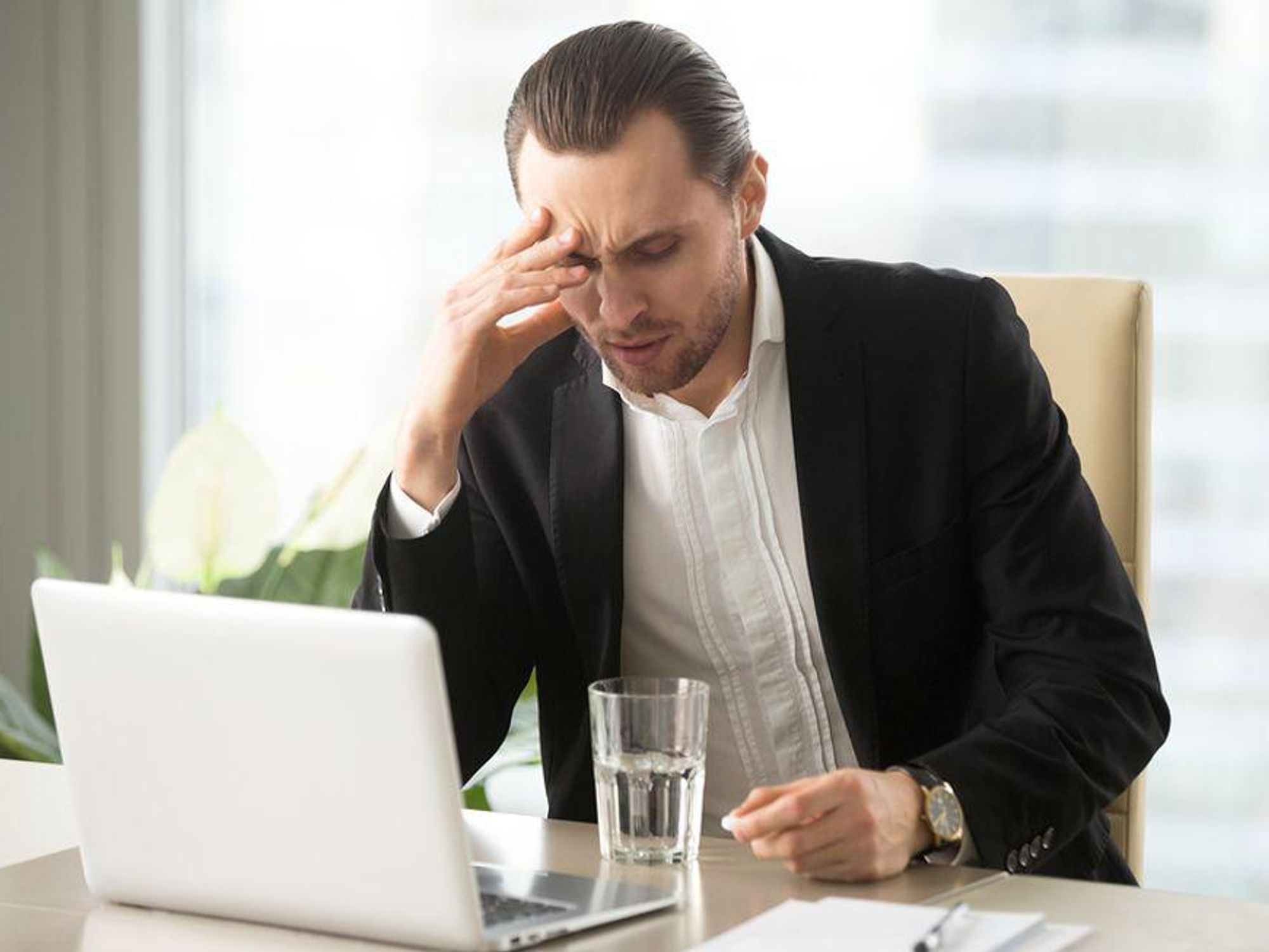 An executive working long hours shows signs of stress.