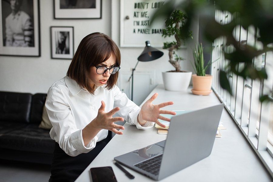 Angry/frustrated woman on laptop wonders why she keeps getting rejecting from jobs she's qualified for