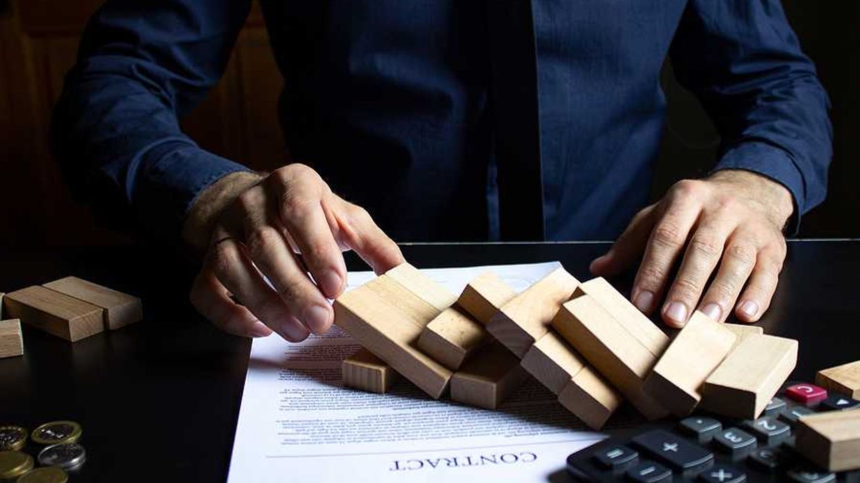 Broken foundation concept; businessman destroys foundation of blocks