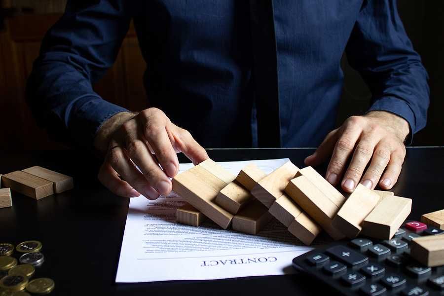 Broken foundation concept; businessman destroys foundation of blocks