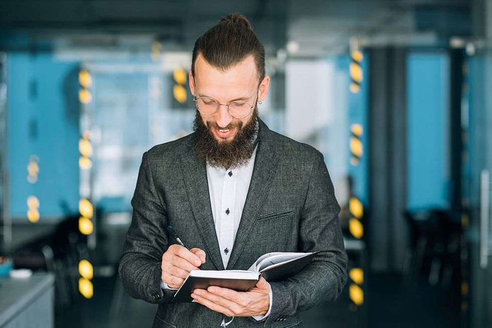 Business man uses a journal to keep track of professional skills and accomplishments.