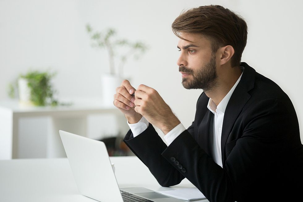 Businessman on laptop thinks about career goals in preparation for a meeting with his boss