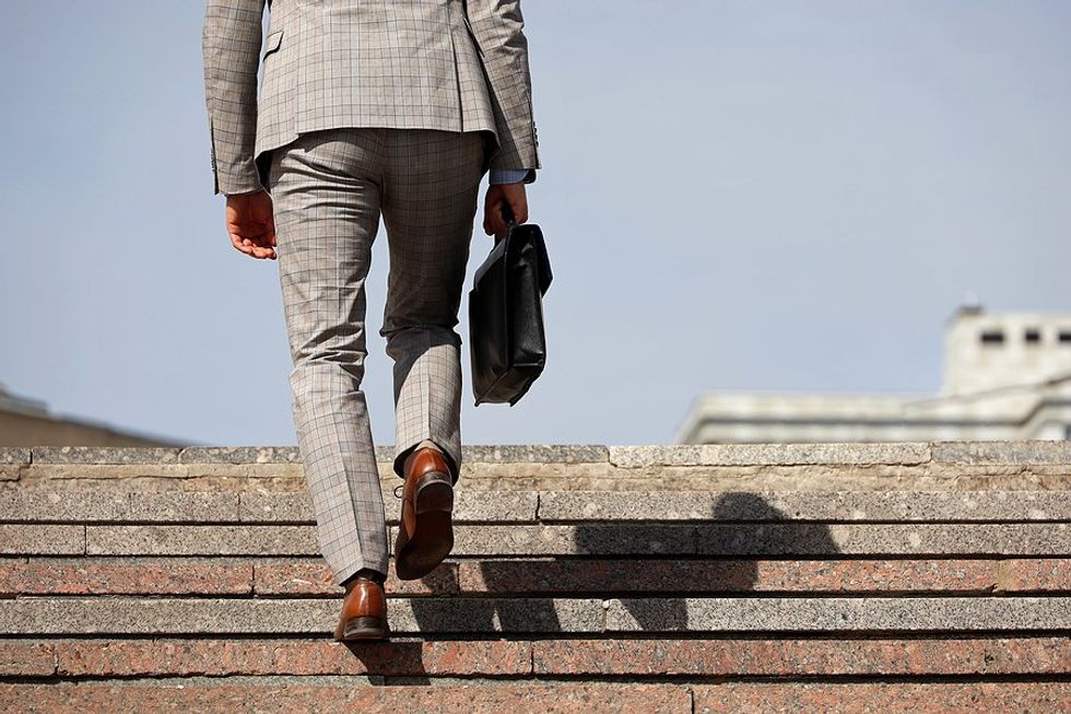 Businessman/professional walks up stairs carrying a briefcase