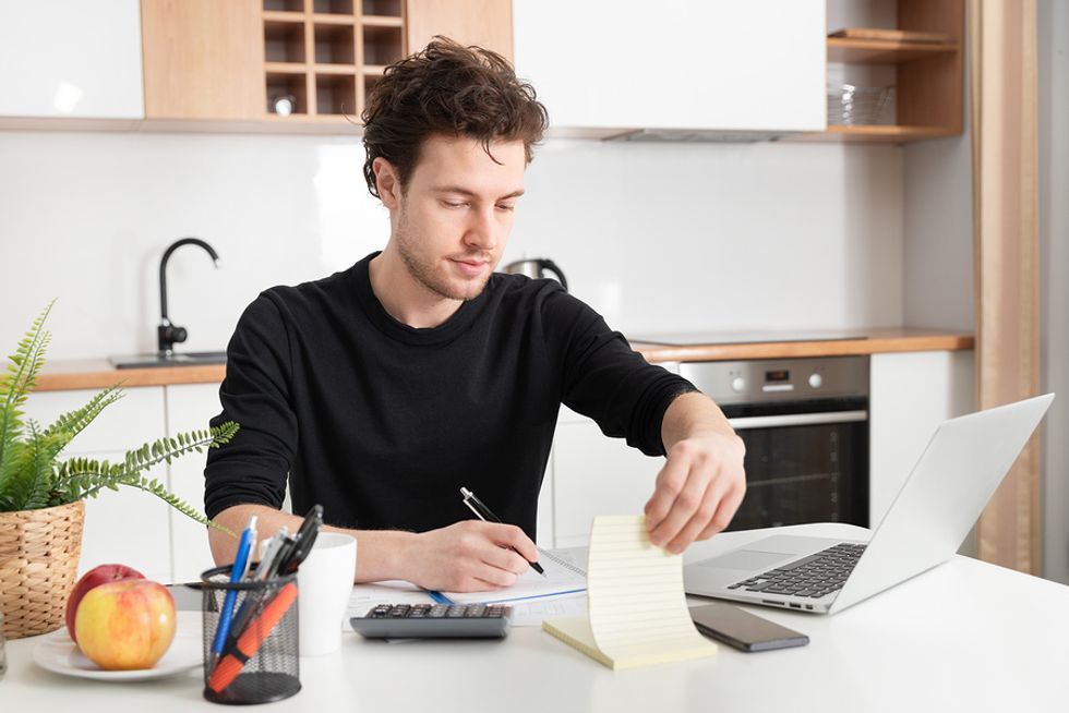 Businessman takes notes while working from home.