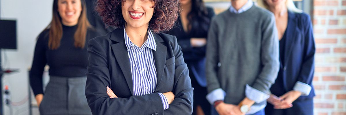 Career coach stands with her arms crossed in front of her clients