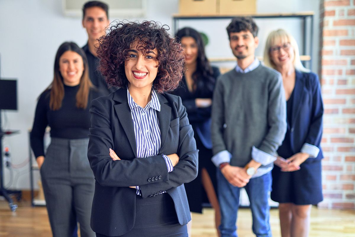 Career coach stands with her arms crossed in front of her clients