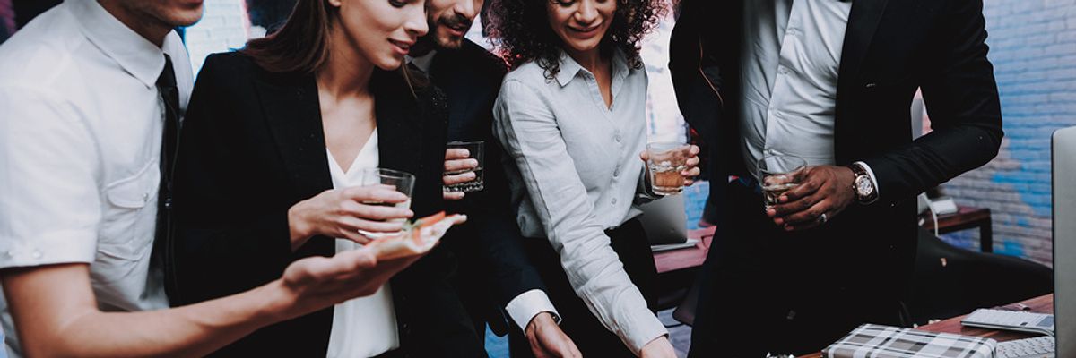 Co-workers eat pizza at a holiday office party