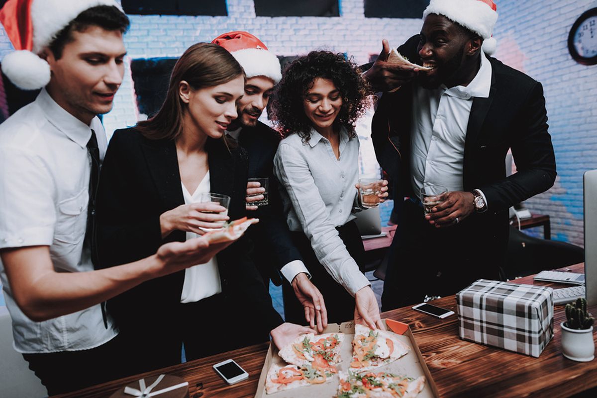Co-workers eat pizza at a holiday office party