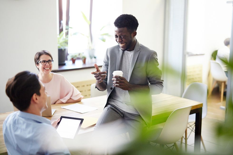 Co-workers share a laugh during a meeting after agreeing to buy coffee