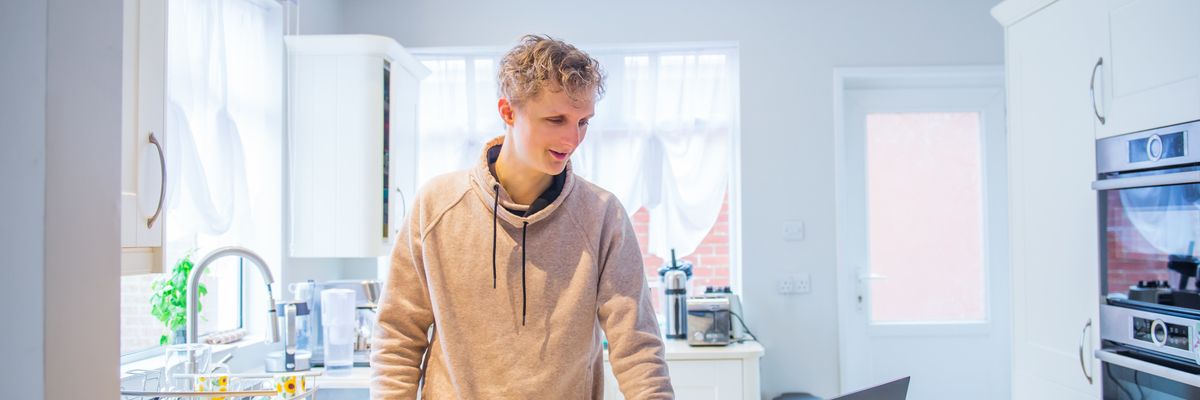 College student attends to some freelance work while preparing a snack.