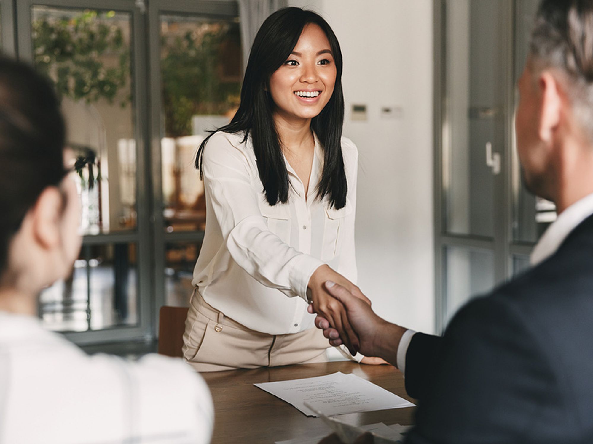 Confident woman shakes the hand of the hiring manager before a job interview