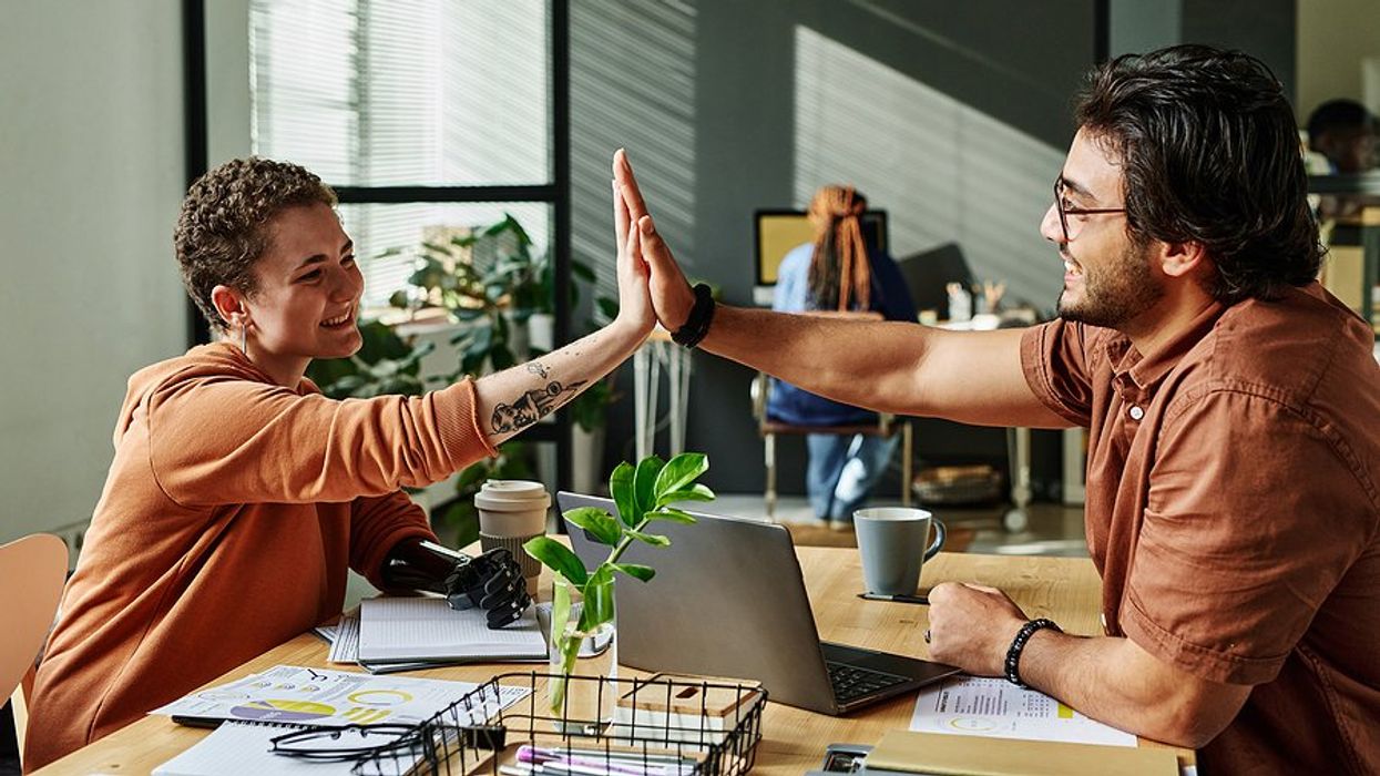 Coworkers in a healthy work environment high-five each other