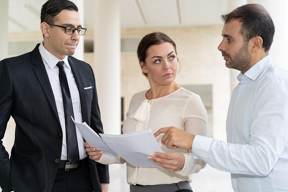 Coworkers talk about a project while a difficult stakeholder interrupts