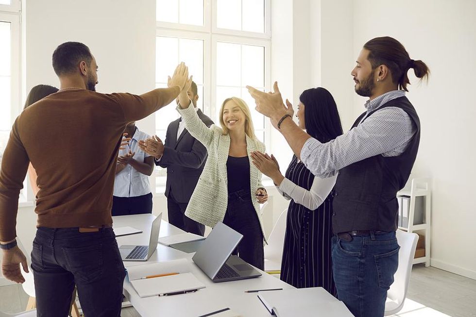 Employees celebrate, high five, and motivate each other at work