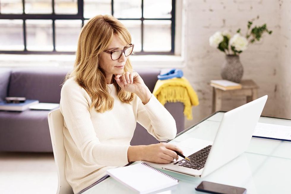 Employer on laptop reviews a candidate's social media accounts during the hiring process