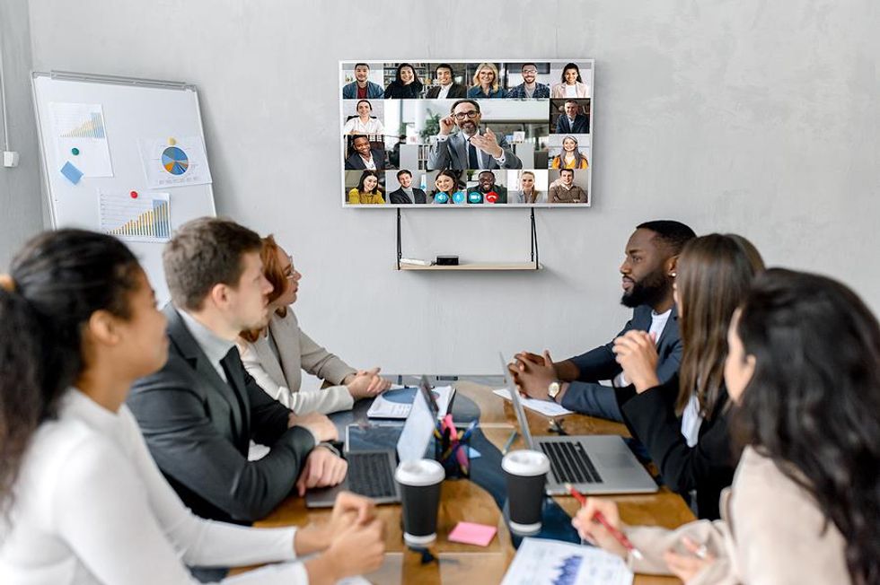 Executive leads a team meeting with hybrid, in-office, and remote employees
