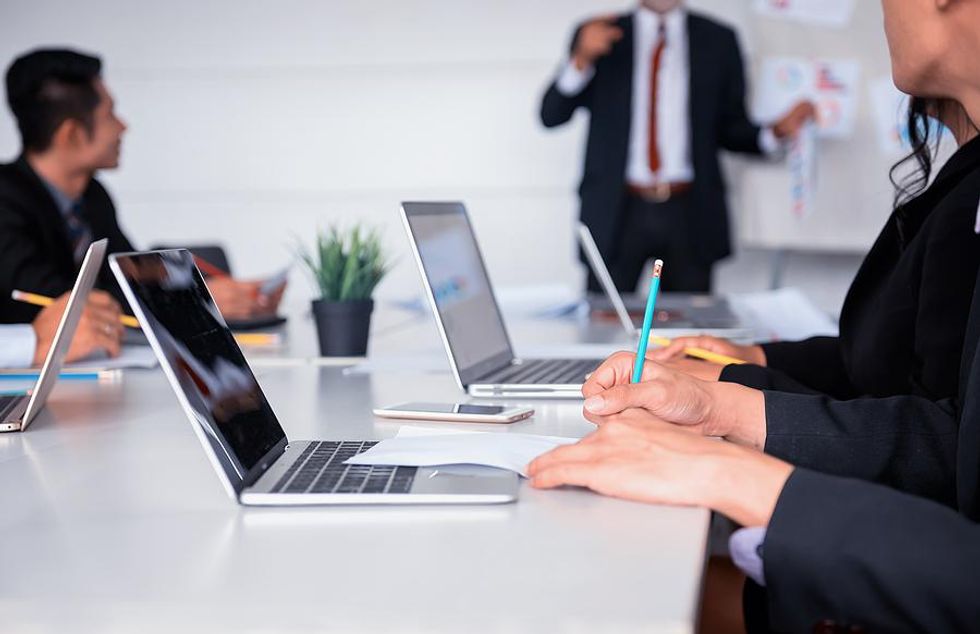 Executive takes notes during an employee presentation to the C-suite