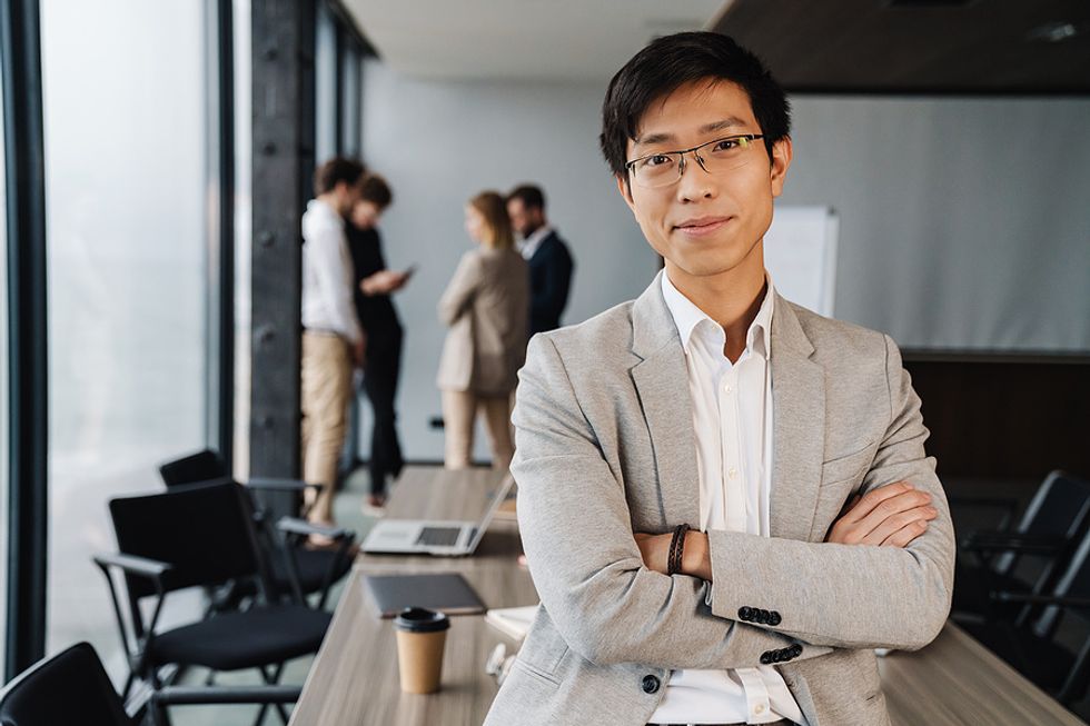 Executive with a good personal brand stands with his arms crossed