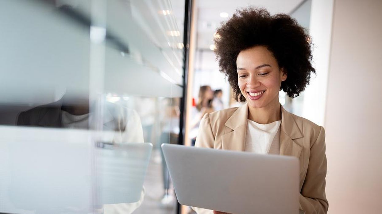 Female leader at work smiles while working on her laptop