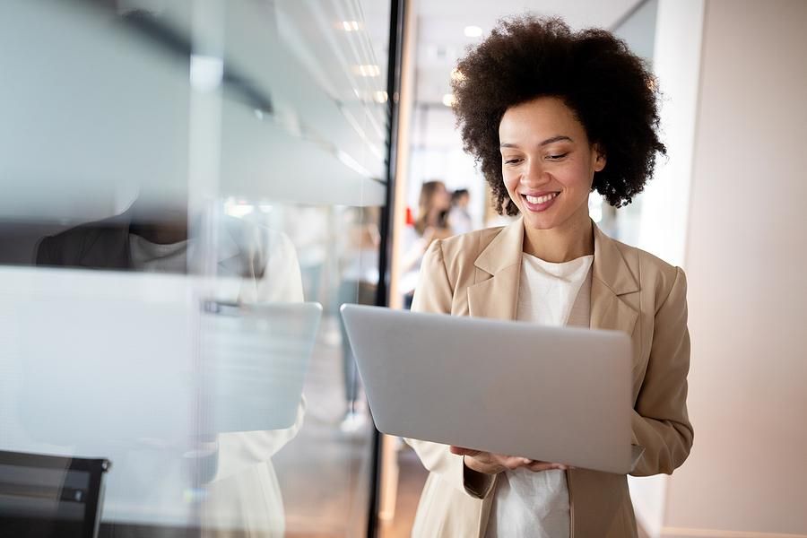 Female leader at work smiles while working on her laptop