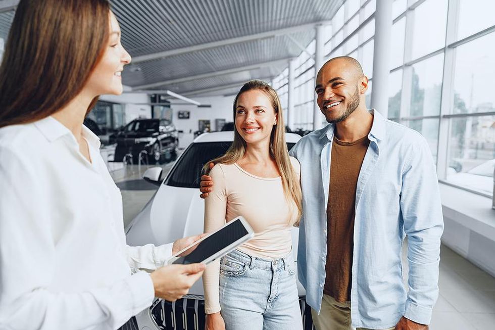 Female salesperson helps a couple buy a car