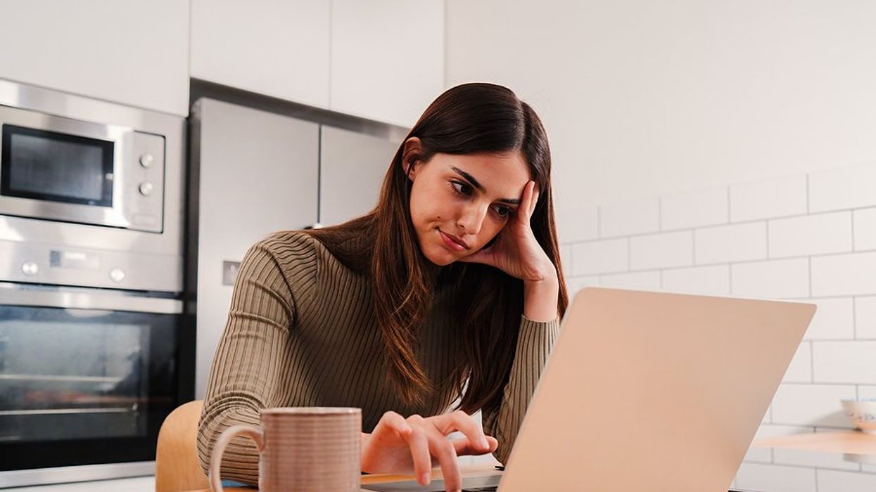 Frustrated/bored woman on laptop feels bad for being unproductive in her job