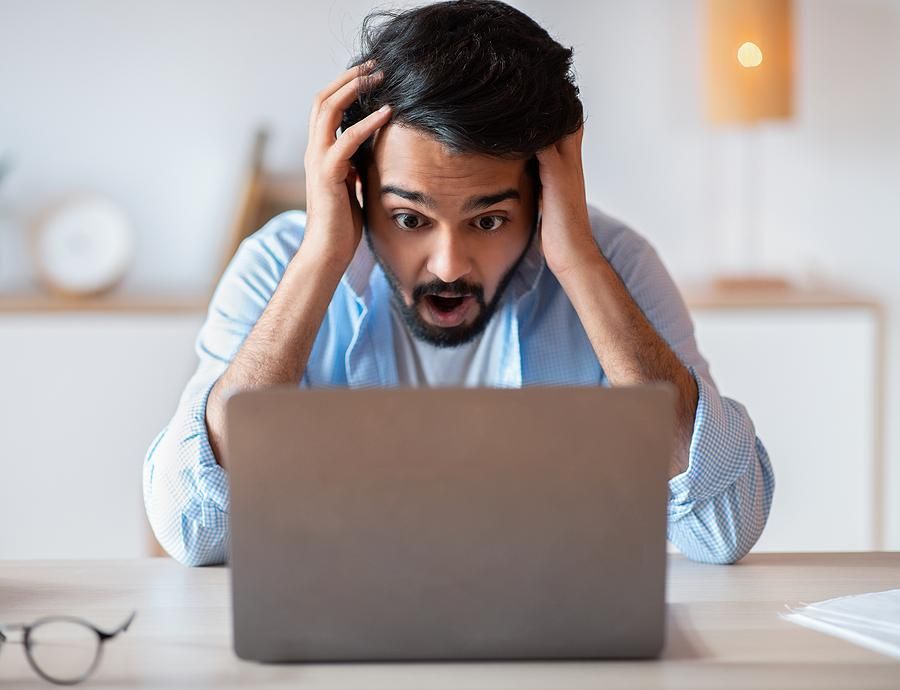 Frustrated man on laptop is miserable at work