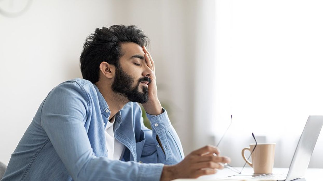 Frustrated/tired man on laptop struggles with job search anxiety and depression