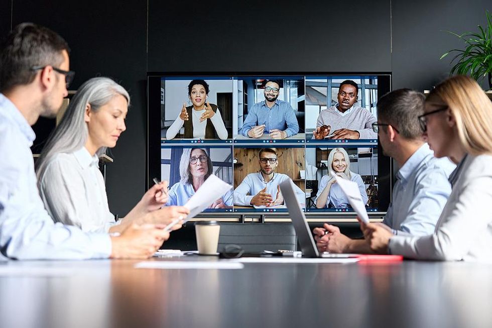 Group of leaders talk during a virtual and in-person business meeting
