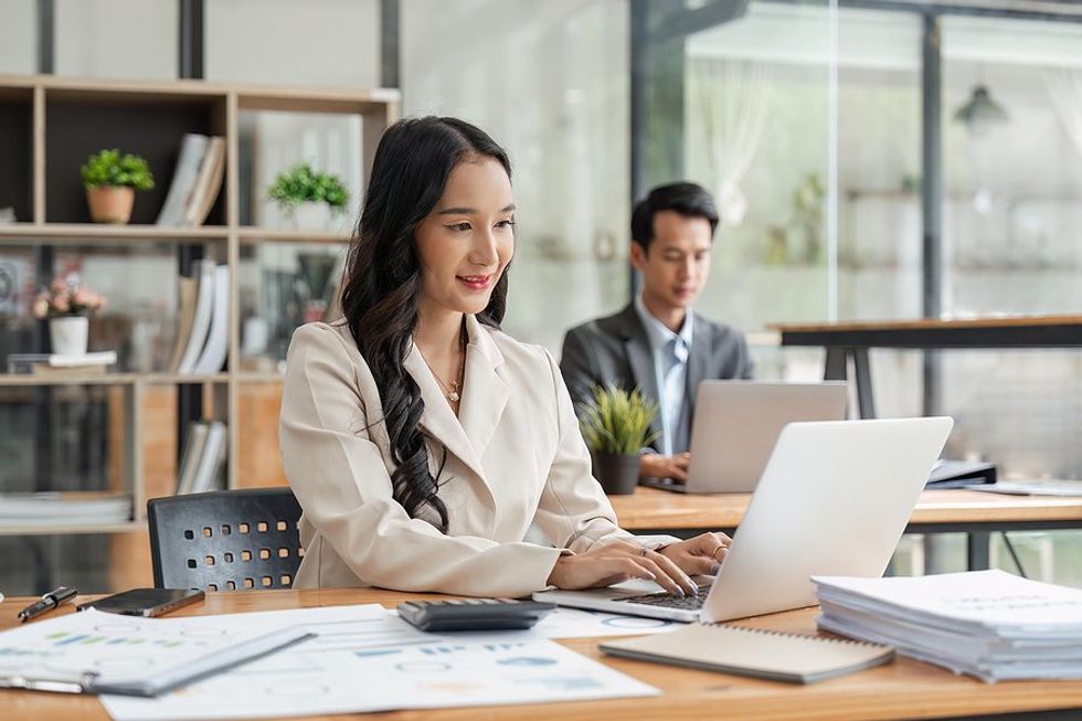 Happy business woman/employee/professional smiles while working on her laptop