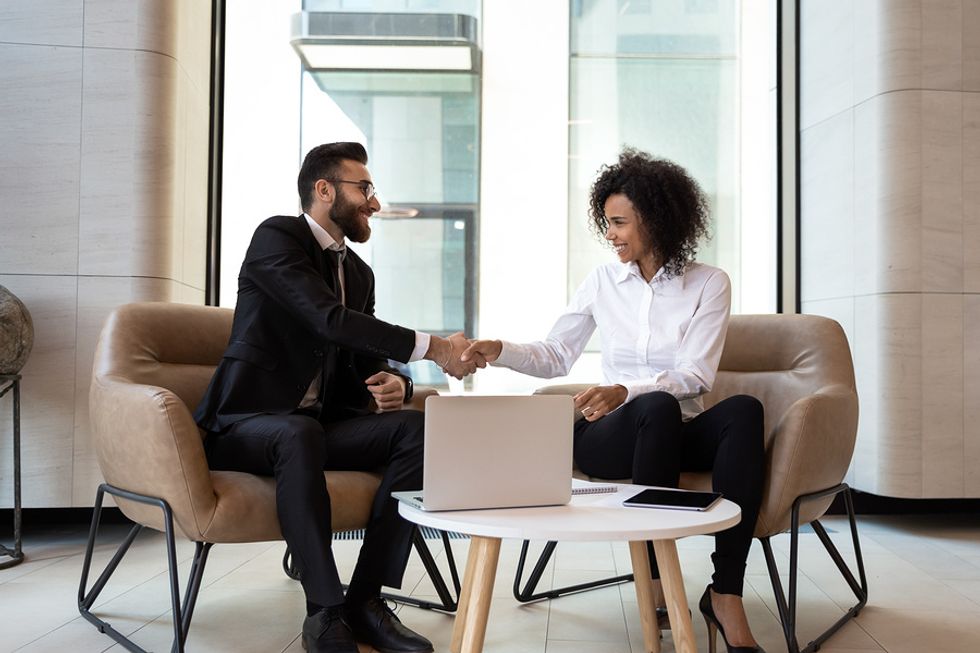 Happy coworkers thank each other and shake hands