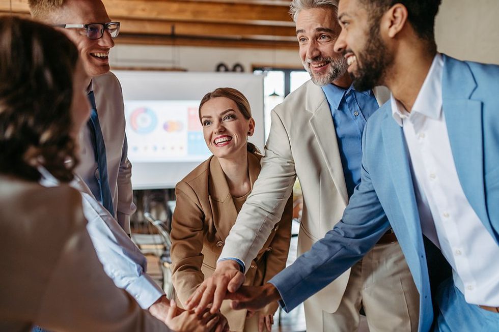 Happy employees huddle up and celebrate at work