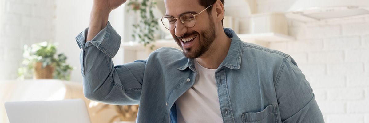 Happy/excited man on laptop finds out he got the job he interviewed for