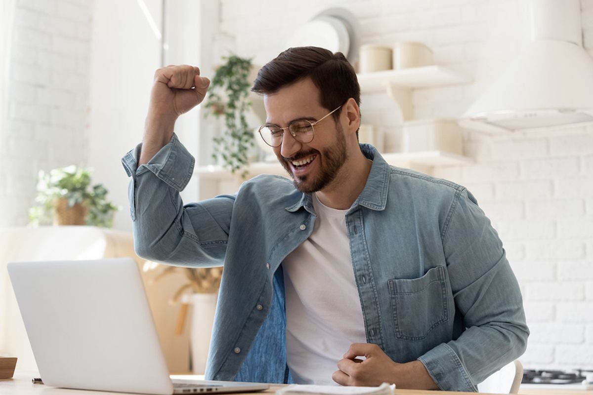 Happy/excited man on laptop finds out he got the job he interviewed for