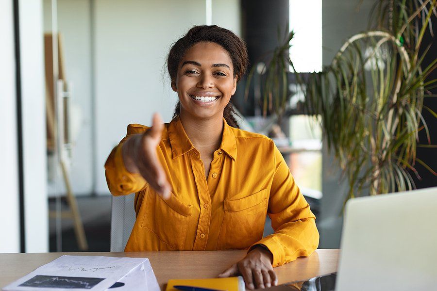 Happy hiring manager shakes a job candidate's hand before asking interview questions