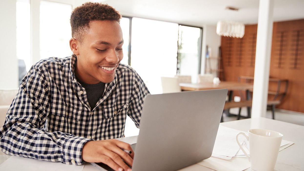 Happy man on laptop changing his resume fluff to marketable facts and results