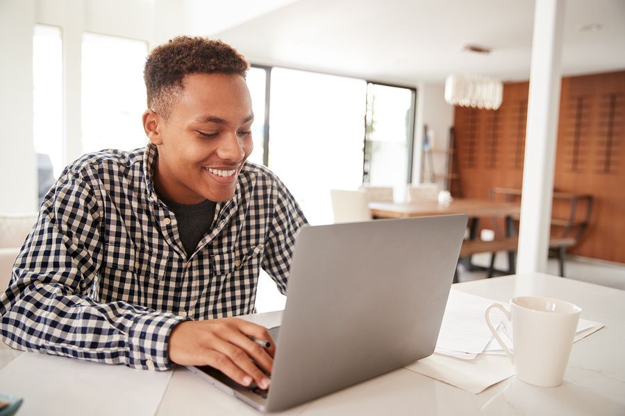 Happy man on laptop changing his resume fluff to marketable facts and results