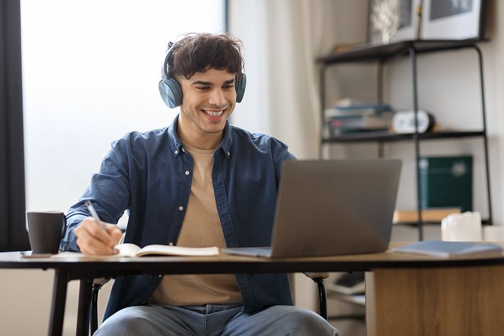 Happy man on laptop discovers his unique value add (UVA) during his Work It DAILY Premium Trial