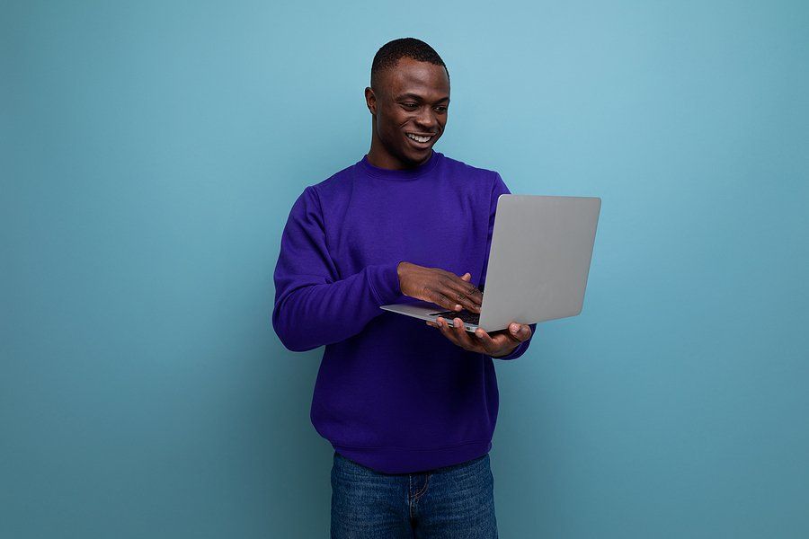 Happy man on laptop follows up with an employer after a job interview